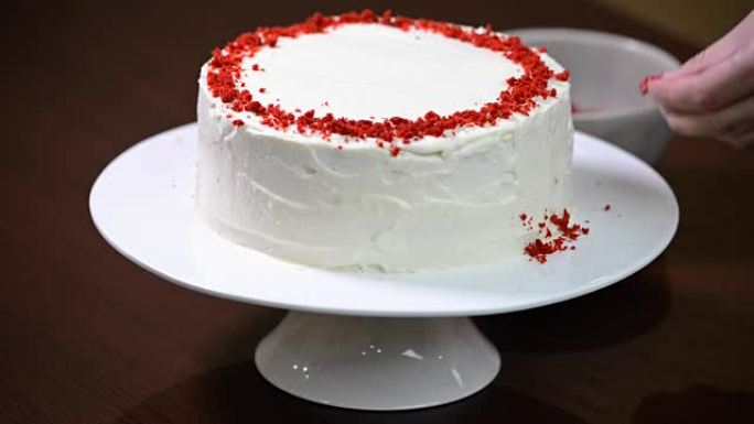 女人的手装饰蛋糕。红色天鹅绒蛋糕