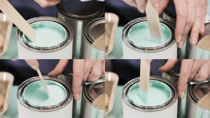 用木棍在金属漆罐中混合油漆。