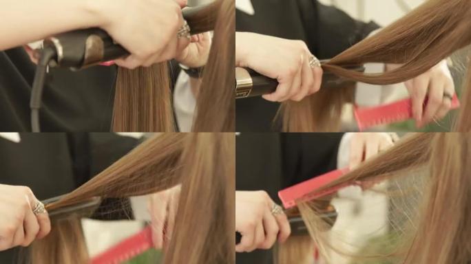 发型师在美容院使用发钳和梳子来拉直时尚模特。在美发沙龙的女性发型设计中，近距离美发师拉直长发