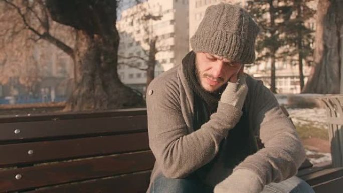 Attractive young man sitting on a park bench talki