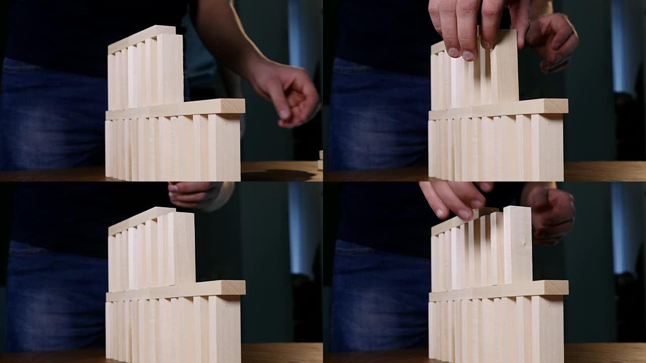年轻人的手在玩jenga时建造了一座积木塔