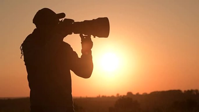 男人在风景秀丽的日落时用数码相机拍照。慢动作镜头