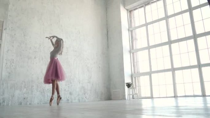优雅的年轻芭蕾舞演员在巨大的光窗的背景下跳舞。经典芭蕾舞短裙和尖角芭蕾舞演员