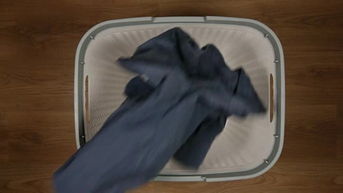 俯视图: 一块脏布掉到地板上的洗衣篮上-慢动作