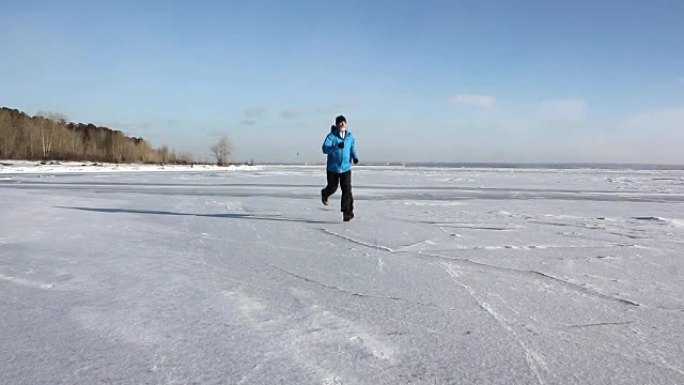穿着蓝色夹克的男人在俄罗斯Ob水库的一条冰冻河流的冰上奔跑
