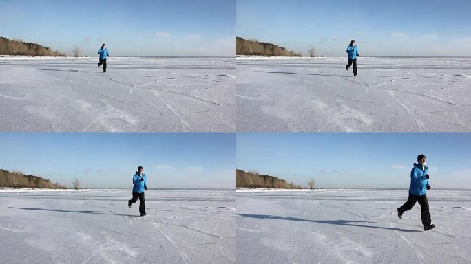 穿着蓝色夹克的男人在俄罗斯Ob水库的一条冰冻河流的冰上奔跑