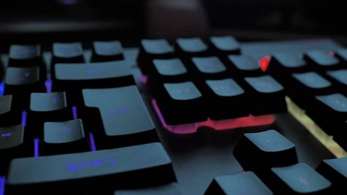 发光的键盘黑客风格在夜晚的工作场所闪烁着不同的浅色