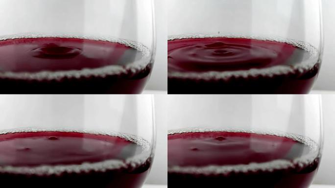 红酒掉落在白色背景上的酒杯中，营养保健概念，用高速相机拍摄