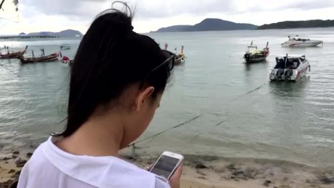 年轻女子用智能手机拍照出海