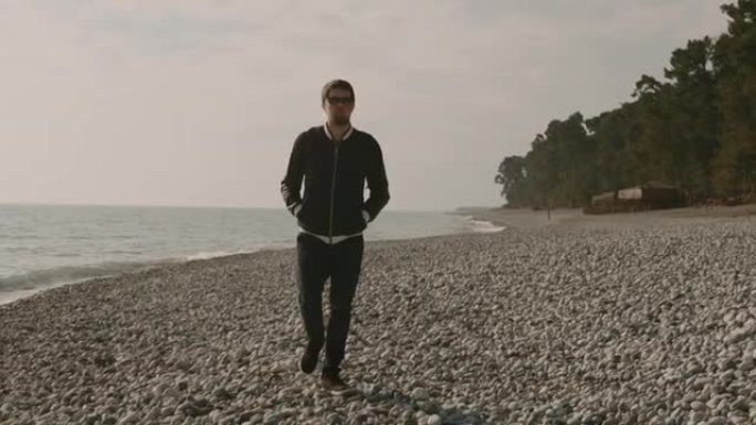 一个孤独的人在石质海滩上漫步，海浪拍打着岸边