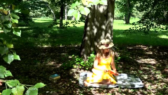 女人坐在格子上，在树影下的公园里看书。全高清