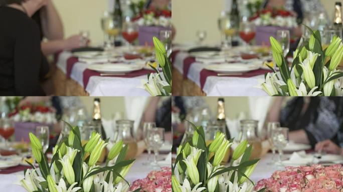 节日餐桌上装饰着百合花和玫瑰的插花