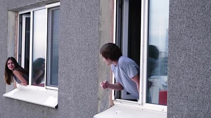 年轻人透过窗户与邻居交谈。年轻人抽烟，从窗户与邻居交谈