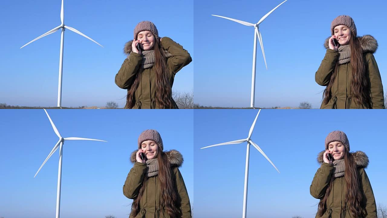 干净的力量，手拿手机的女孩微笑着，在现代风车和天空的背景下通过电话交谈