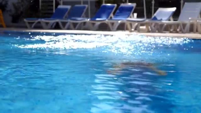 年轻漂亮的女人跳进盆里，然后从水下冒出来。黑发女孩在游泳池游泳，阳光明媚的日子放松。暑假或假期概念。