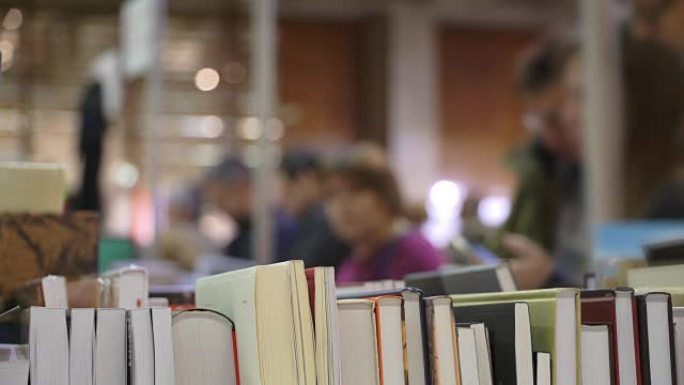 书店的书架上有书堆，年轻人竖起大拇指，看着书。人们看书。学生在书店看书或课本。在书店买书。概念学习和