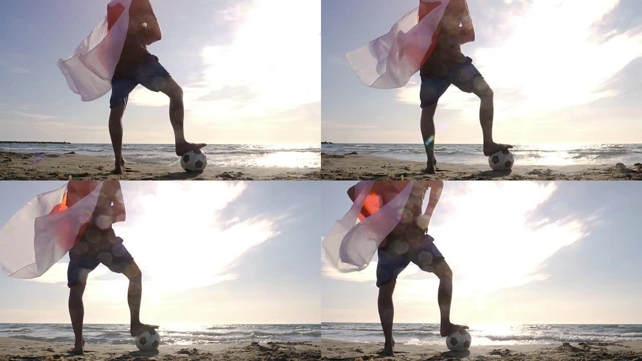 戴着日本国旗的年轻人作为超级英雄斗篷，脚踩着足球站在海边的沙滩上，日落时看着海滩上的海洋摄像机ste