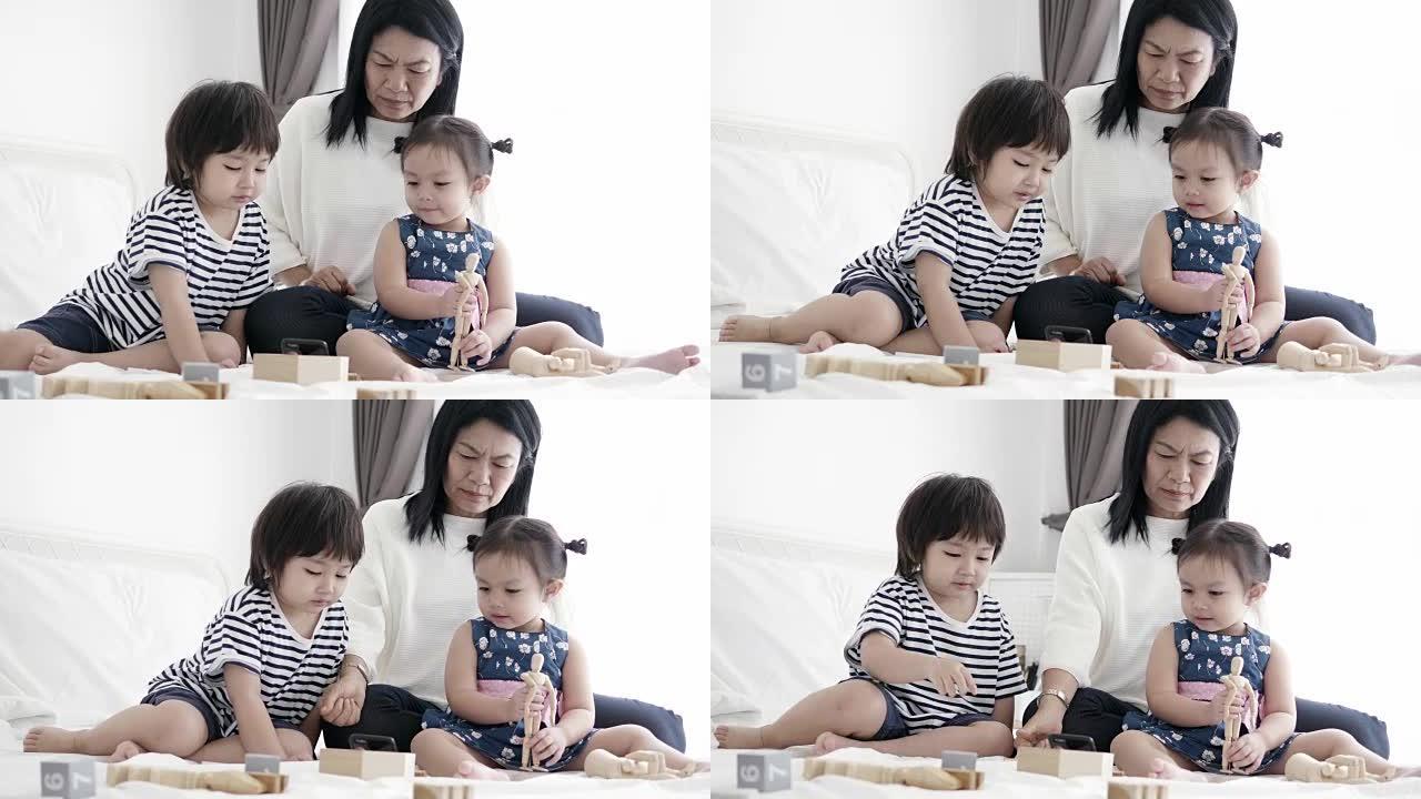 泰国祖母和她的侄女和孙子在她的卧室里用智能手机观看卡通表演的休闲放松活动
