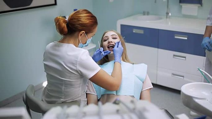 戴面具的女性口腔科医生。女医生在工作。照镜子的病人。