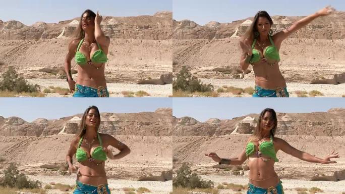 漂亮的女舞者。肚皮舞。沙漠。性感的绿蓝裙舞