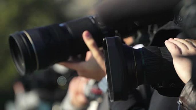 几位摄影师和摄像师在活动中使用摄像机和三脚架上的长镜头录制视频和照片