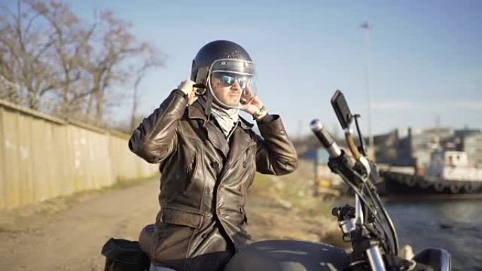 在寒冷的晴天，高加索男子摩托车手在港口附近戴头盔