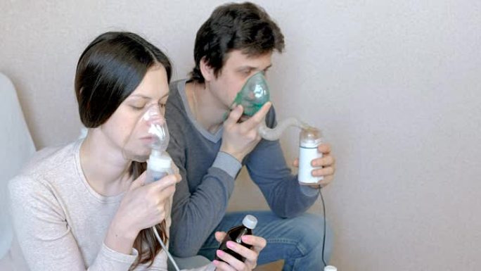 使用雾化器和吸入器进行治疗。男人和女人通过吸入器面罩吸气。前视图。
