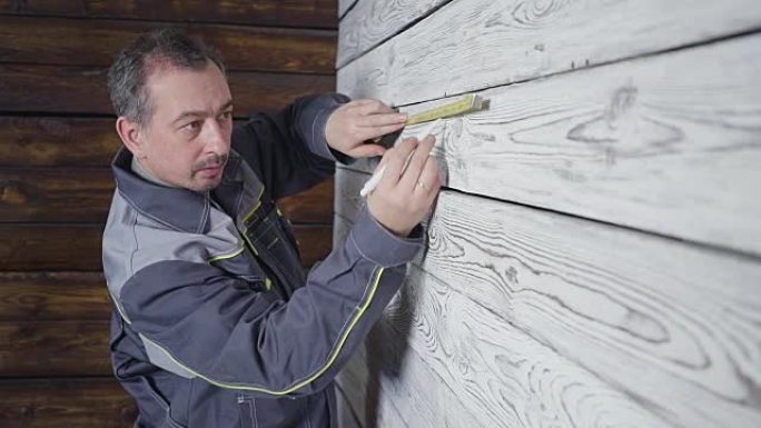 工人用尺子测量木墙