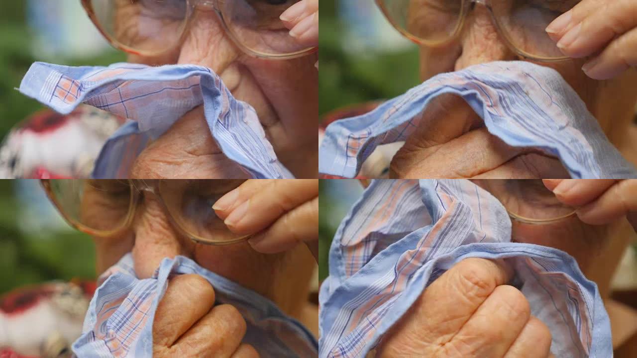 戴眼镜的祖母在户外把鼻子吹到手帕上。一个生病的老妇人的肖像。关闭慢动作