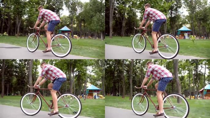运动男在公园路骑自行车。年轻英俊的男人在户外骑老式自行车。健康积极的生活方式。侧视图特写慢动作低角度