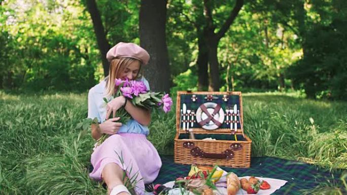 快乐微笑的年轻女子在户外野餐时在公园里享受一束鲜花