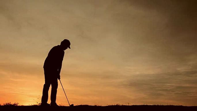 剪影男高尔夫球手正在日落温暖的灯光下打高尔夫球