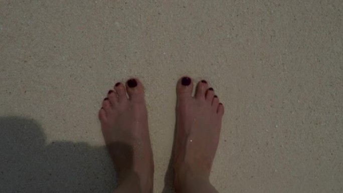 沙滩上的海浪，海沫和妇女的赤脚。