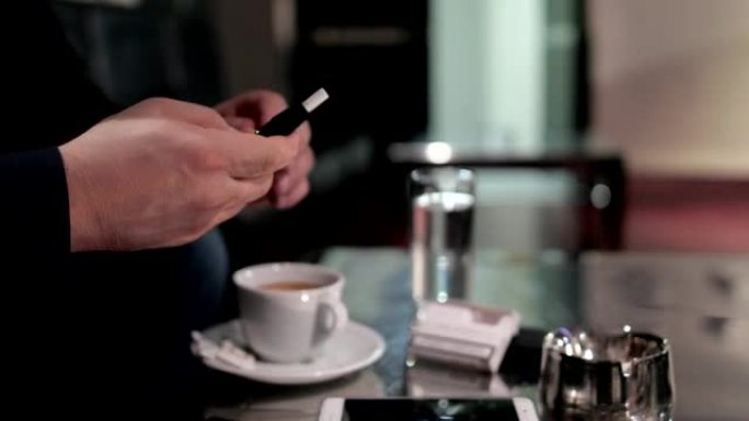 Young man smoking e cigarette and drinks coffee