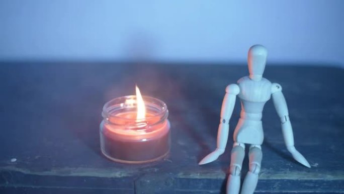 黑色背景上的木制娃娃，罐子里的蜡烛