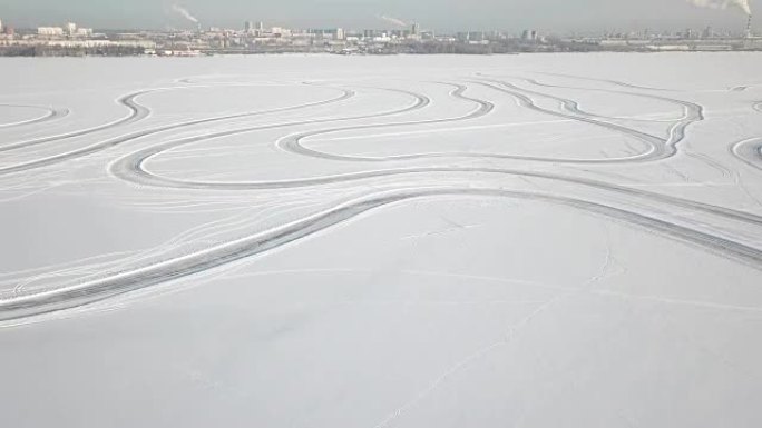 冬天的风景，雪上的轮胎痕迹，天空中的地平线，太阳和云。雪沙漠和雪中汽车的轨迹。雪地上的足迹