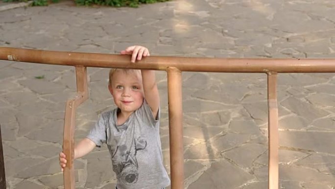 小男孩爬上公园凉亭的篱笆。