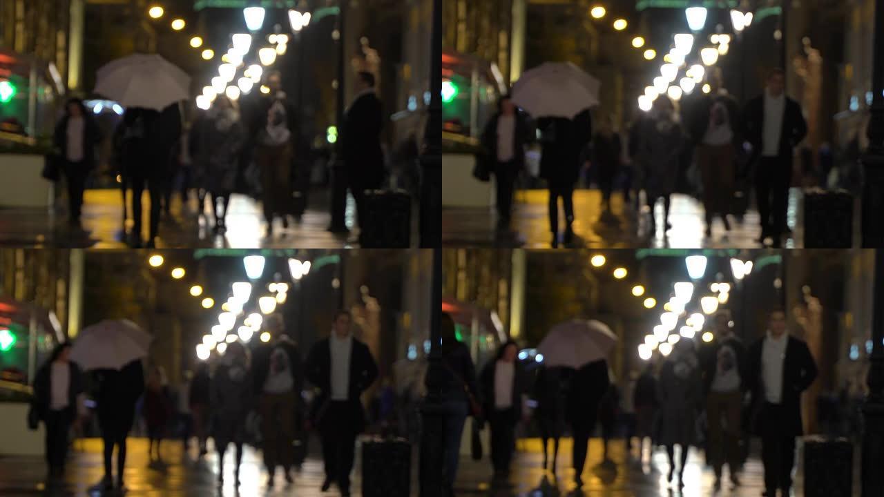 夜城雨。下雨的夜晚在城市街道上，有路灯，雨水中有闪亮的沥青。无法辨认的行人，年轻人，带白伞的女孩。现