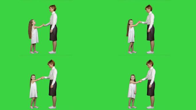 母亲和孩子在绿色屏幕上握手，色度键