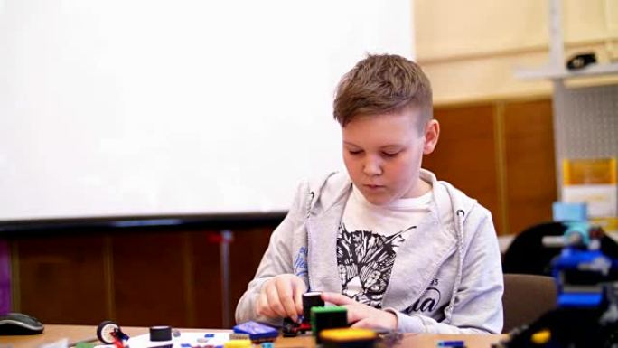 11岁的男孩，从立方体，盘子，电路，电线在设计师中扮演角色。一个小发明家从设计师的不同部分创建机器人