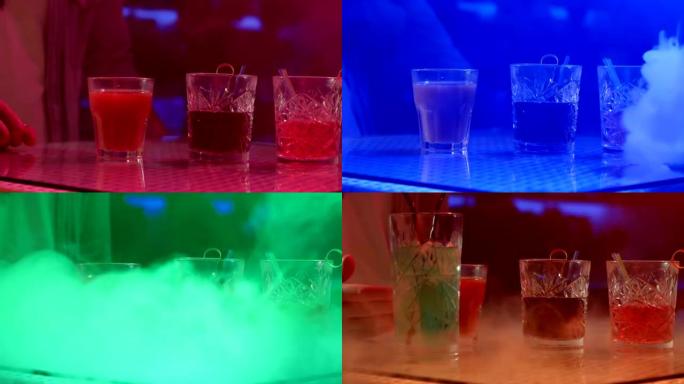 在彩灯背景下的烟雾中，酒吧柜台上有饮料和吸管的眼镜