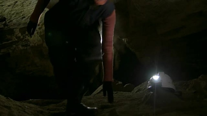一群年轻的洞穴学家在黑暗的狭窄洞穴中爬上