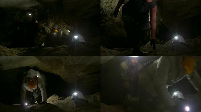 一群年轻的洞穴学家在黑暗的狭窄洞穴中爬上