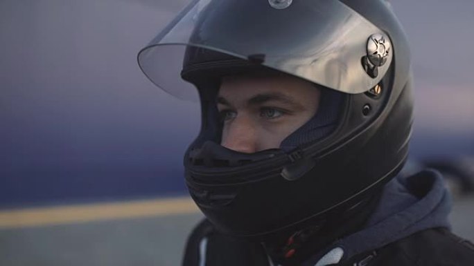 街上戴着黑色头盔的年轻迷人摩托车手。男子摩托车手