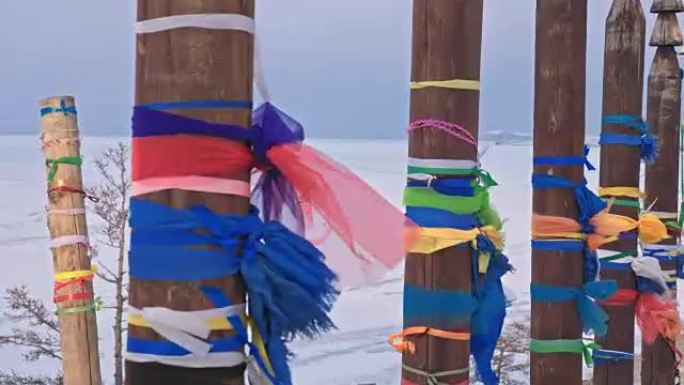 冬天在贝加尔湖圣地用彩带的佛教仪式杆。神圣的地方。木杆上有很多强加的彩色襟翼和织物制成的丝带。