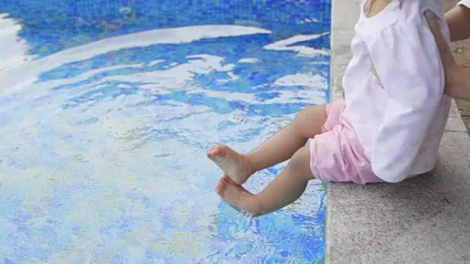 一个小女孩在度假村游泳池踢水。