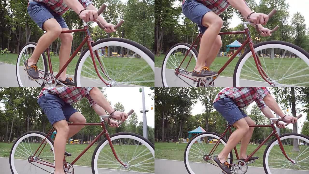 无法辨认的年轻人骑着老式自行车。运动男在公园骑自行车。健康积极的生活方式。低角度视图特写慢动作侧视图
