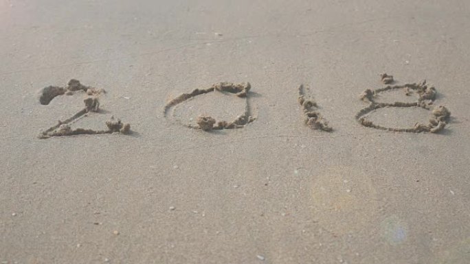 4k快乐新2018年。2018在沙滩上写波浪飞溅。新年快乐倒计时从2017年2018年视频镜头背景转