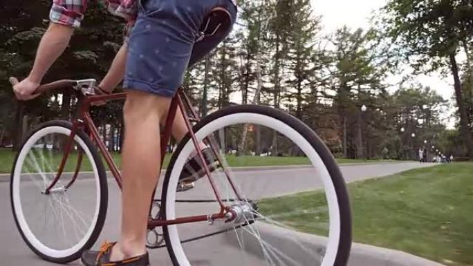 年轻人在公园路骑老式自行车。运动男在户外骑自行车。健康积极的生活。关闭低角度视图慢动作