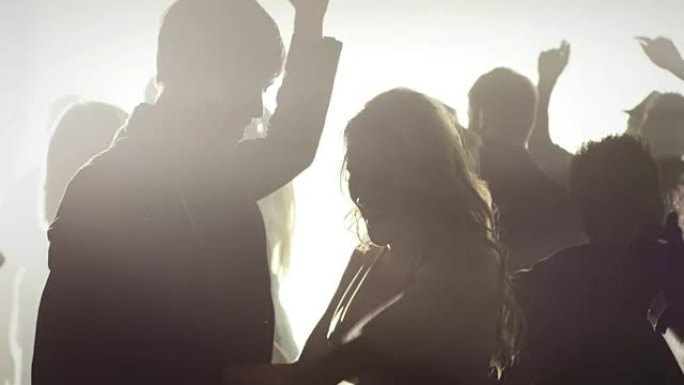 一群人在俱乐部跳舞的烟熏房间里的剪影